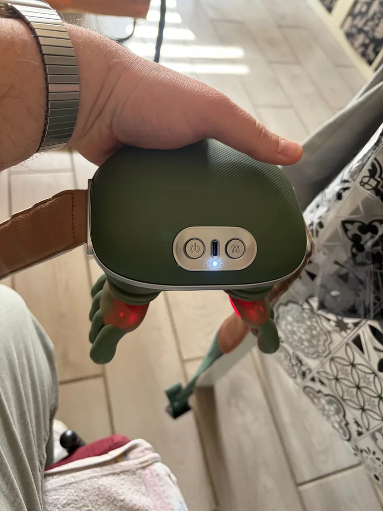 The Nodly massager held in one hand, switched on, the red heating LEDs visible under the fingers