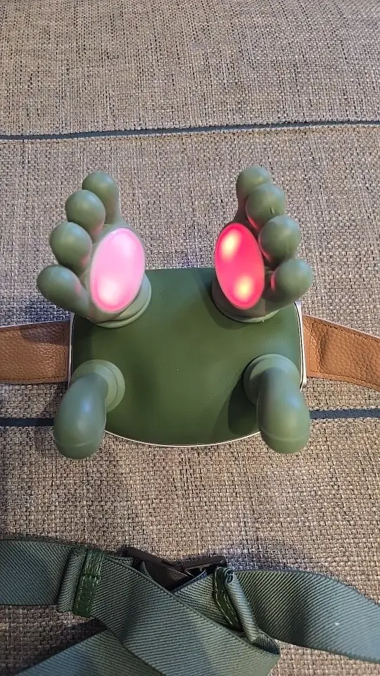 Top view of the Nodly massager, both heating plates glowing pink beneath the fingers